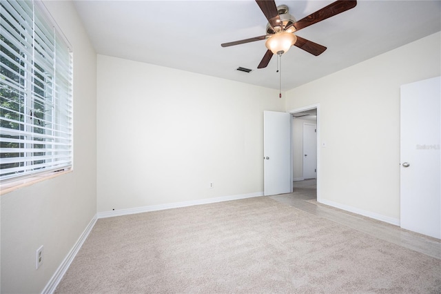 spare room with light carpet, baseboards, and a ceiling fan