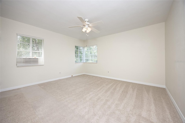 spare room with light carpet, ceiling fan, and baseboards