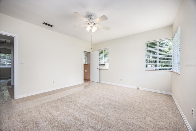 unfurnished room with ceiling fan, light carpet, and plenty of natural light