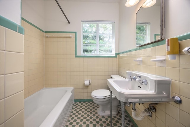 bathroom with tile walls, toilet, a washtub, walk in shower, and a sink