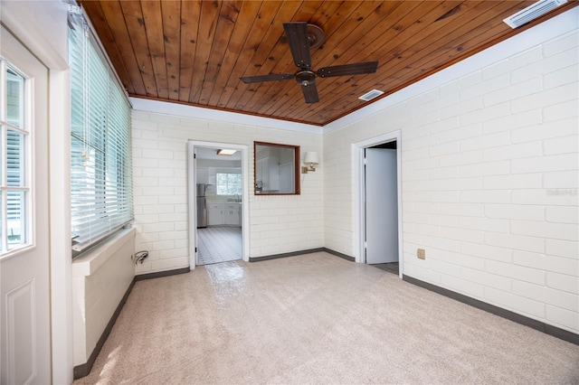 carpeted empty room with a ceiling fan, wood ceiling, visible vents, and brick wall