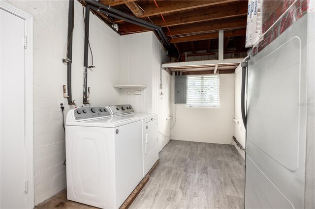 washroom with washing machine and dryer, light hardwood / wood-style flooring, and electric panel