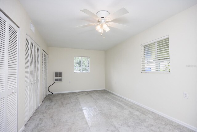 unfurnished bedroom featuring ceiling fan, two closets, and light colored carpet