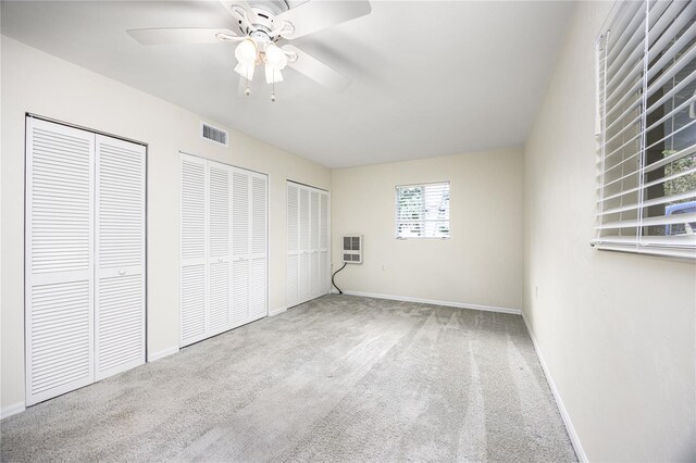 unfurnished bedroom with baseboards, visible vents, two closets, and carpet flooring