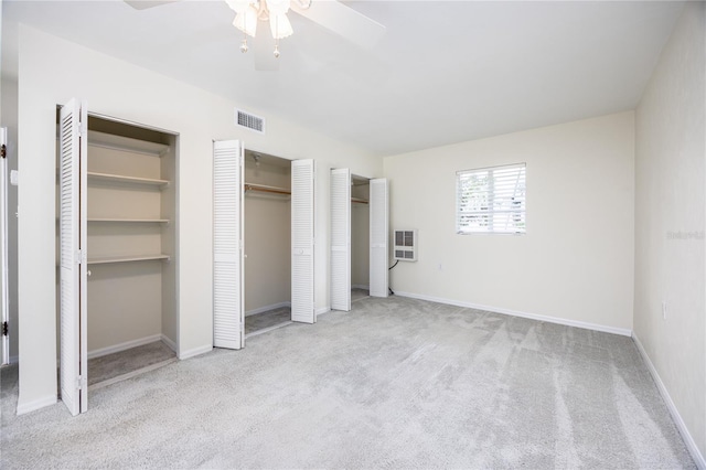 unfurnished bedroom featuring carpet floors, a ceiling fan, baseboards, visible vents, and multiple closets