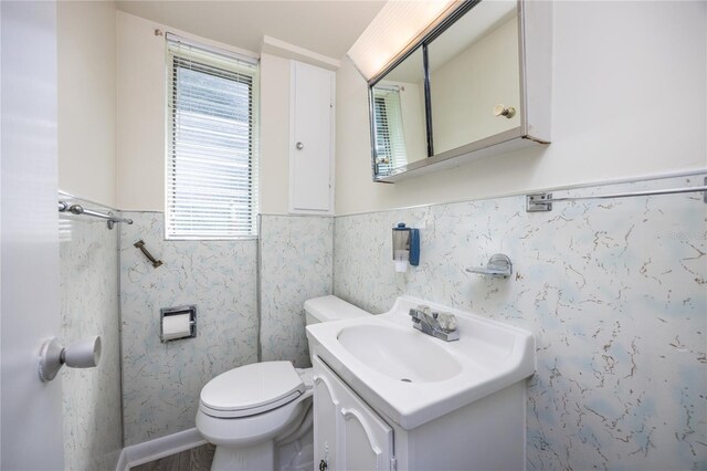 bathroom with plenty of natural light, toilet, vanity, and tile walls