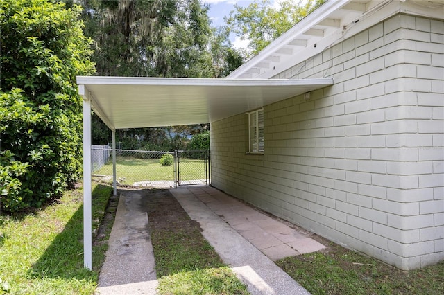 exterior space with an attached carport, fence, and a gate