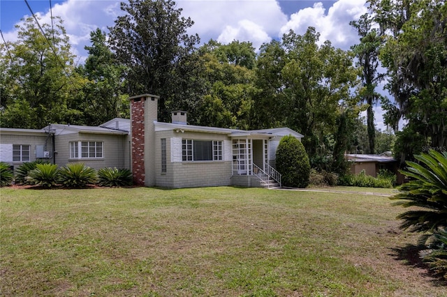 view of front of house with a front yard, brick siding, and a chimney