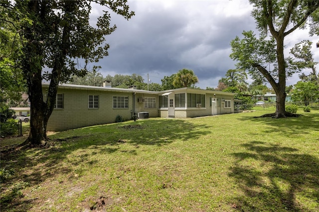 rear view of property featuring a yard, central AC unit, a chimney, and fence