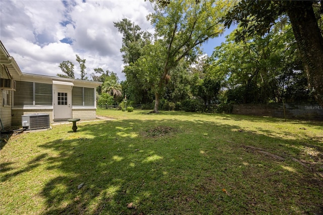 view of yard with central AC and fence