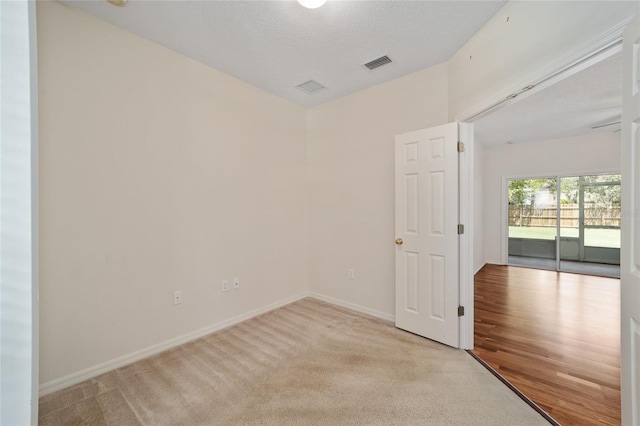 spare room with a textured ceiling and light carpet