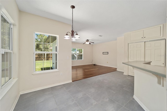 interior space with tile patterned flooring and ceiling fan with notable chandelier