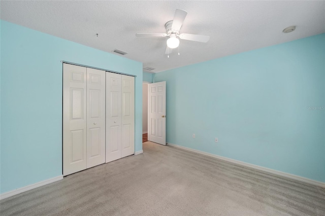 unfurnished bedroom with a textured ceiling, a closet, ceiling fan, and light colored carpet