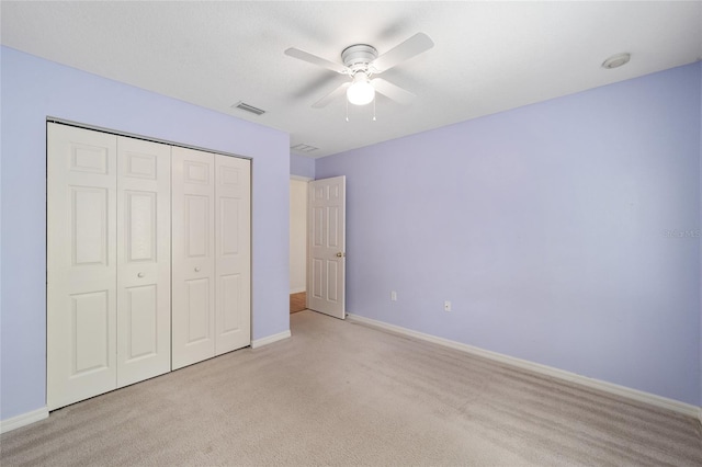 unfurnished bedroom with ceiling fan, light colored carpet, and a closet