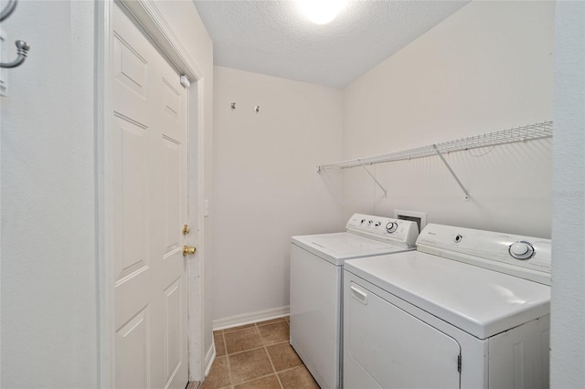 clothes washing area with a textured ceiling, light tile patterned flooring, and washer and clothes dryer