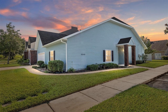 property exterior at dusk featuring a lawn