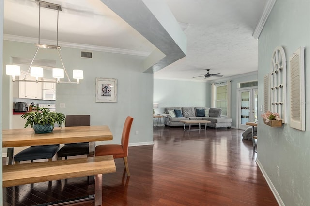 dining space featuring dark wood-type flooring, ceiling fan with notable chandelier, and ornamental molding