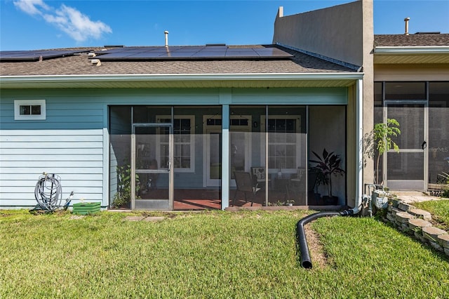 back of house featuring solar panels, a sunroom, and a lawn