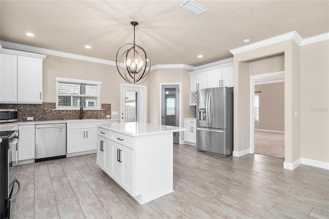 kitchen with white cabinetry, stainless steel appliances, hanging light fixtures, and a kitchen island