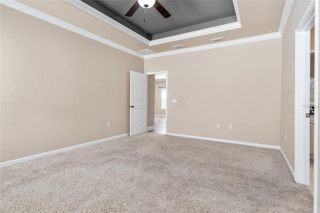 carpeted spare room with ceiling fan, ornamental molding, and a raised ceiling