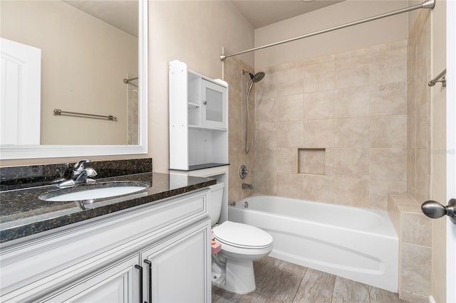 full bathroom featuring vanity, hardwood / wood-style floors, tiled shower / bath, and toilet