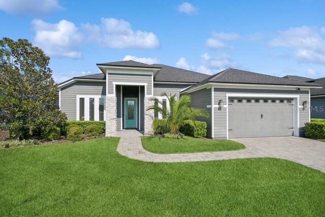 prairie-style house featuring a garage and a front lawn