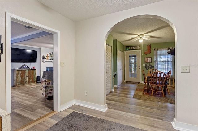 foyer entrance featuring ceiling fan, wood-type flooring, and a textured ceiling