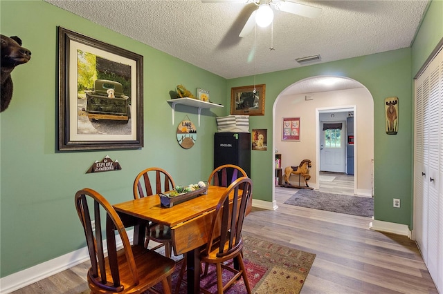 dining room with hardwood / wood-style floors, ceiling fan, and a textured ceiling