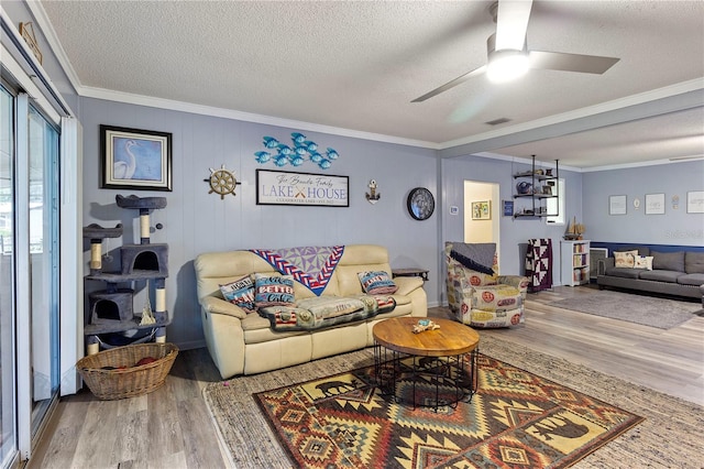 living room with a textured ceiling, ceiling fan, hardwood / wood-style floors, and crown molding