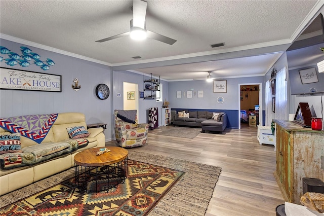 living room with a textured ceiling, light hardwood / wood-style flooring, ceiling fan, and crown molding