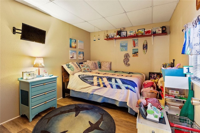 bedroom with light wood-type flooring and a drop ceiling