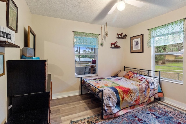 bedroom with a textured ceiling, light hardwood / wood-style flooring, and ceiling fan