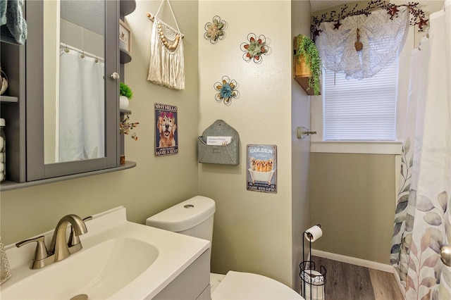 full bath with toilet, baseboards, wood finished floors, and vanity