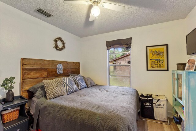 bedroom featuring ceiling fan, hardwood / wood-style floors, and a textured ceiling