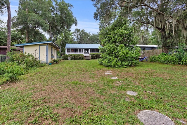 view of yard with an outbuilding, a sunroom, and fence