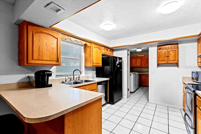 kitchen with stainless steel appliances, sink, washer and dryer, kitchen peninsula, and light tile patterned flooring