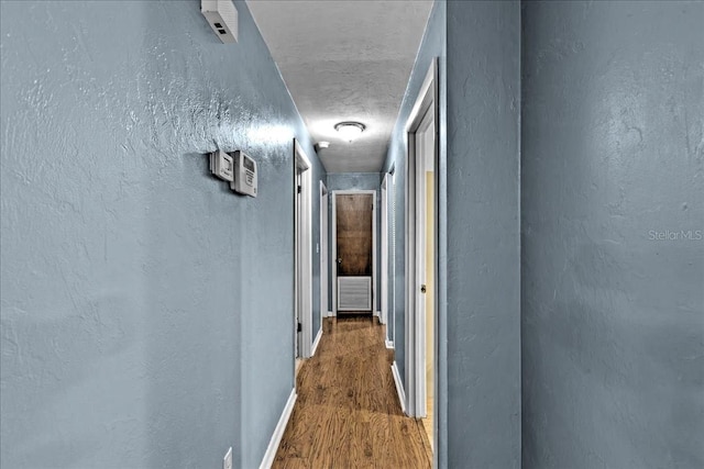 corridor with hardwood / wood-style flooring and a textured ceiling