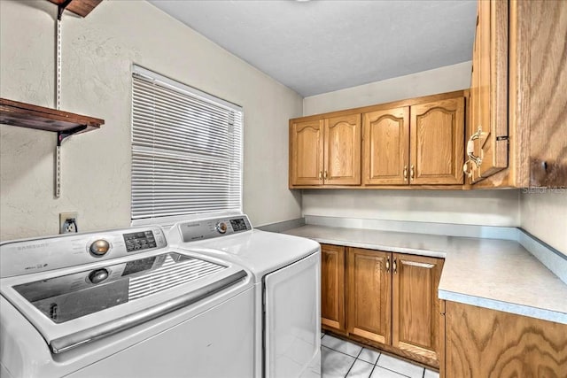 washroom featuring light tile patterned floors, washing machine and clothes dryer, and cabinets