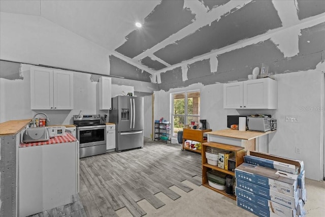 kitchen featuring appliances with stainless steel finishes, vaulted ceiling, and white cabinets