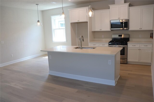 kitchen featuring appliances with stainless steel finishes, light hardwood / wood-style flooring, sink, a center island with sink, and white cabinets