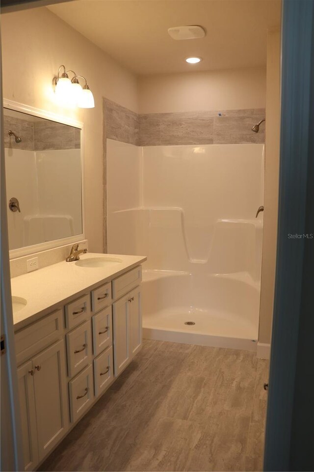 bathroom featuring a shower, hardwood / wood-style flooring, and dual bowl vanity