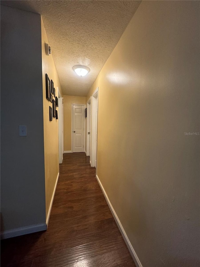 hall featuring dark wood-type flooring and a textured ceiling