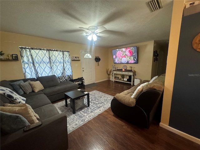 living room featuring ceiling fan, dark wood-type flooring, and a textured ceiling