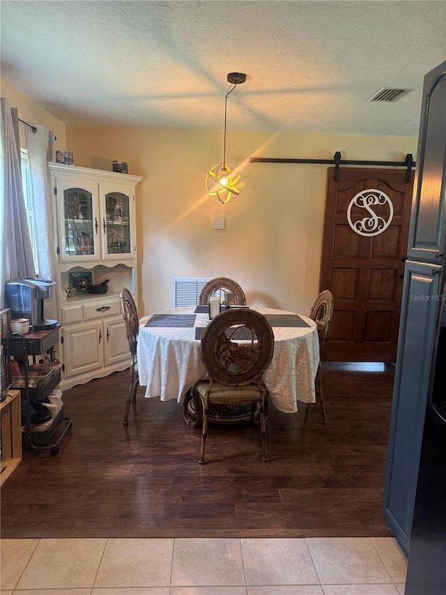 dining space featuring a textured ceiling, light hardwood / wood-style flooring, and a barn door