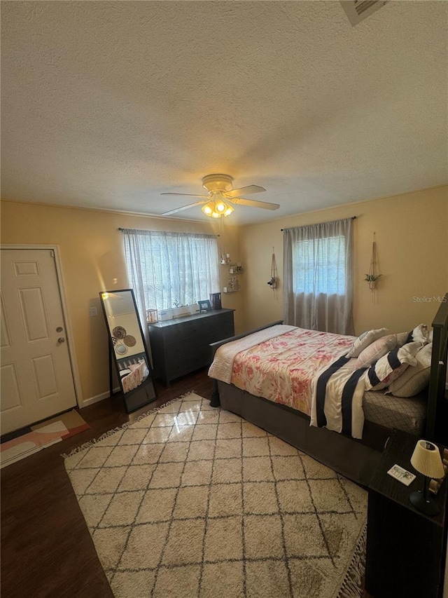 bedroom with ceiling fan, a textured ceiling, and hardwood / wood-style floors