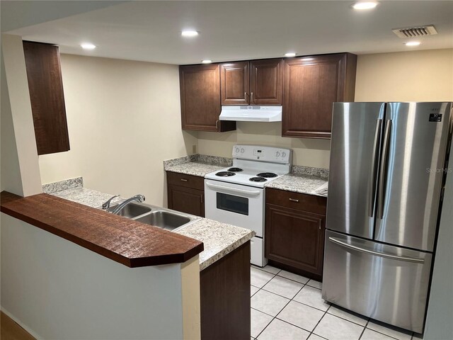 kitchen featuring sink, light tile patterned floors, kitchen peninsula, stainless steel fridge, and white electric range