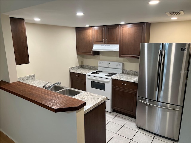 kitchen with under cabinet range hood, white electric range, a sink, visible vents, and freestanding refrigerator