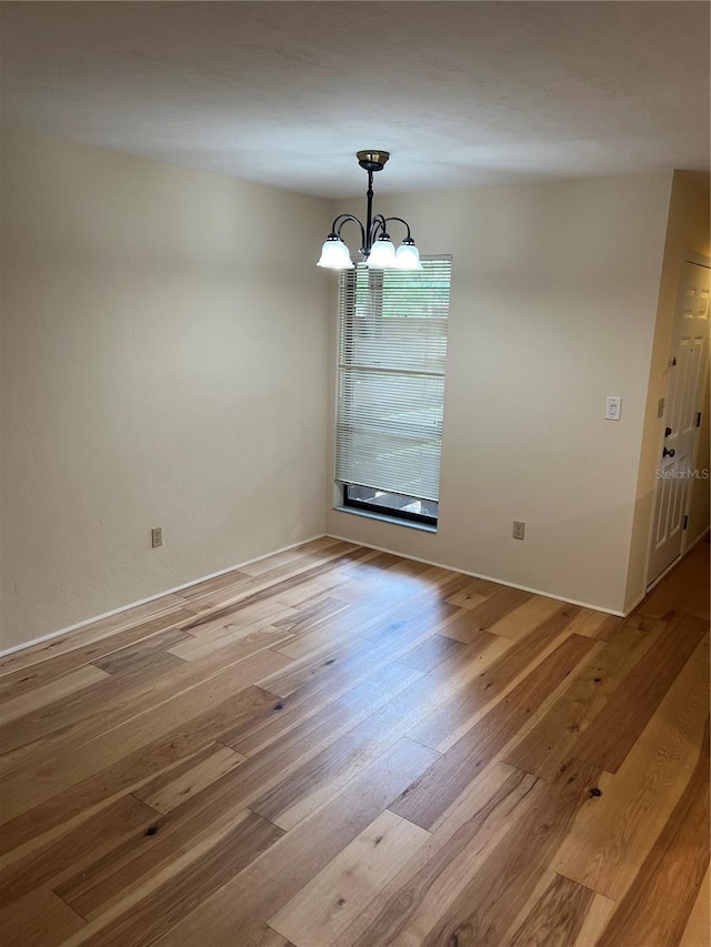 unfurnished dining area featuring a chandelier and light wood-style flooring