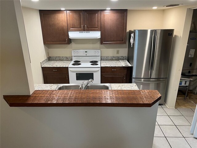 kitchen with stainless steel refrigerator, dark brown cabinetry, light tile patterned flooring, and white electric range