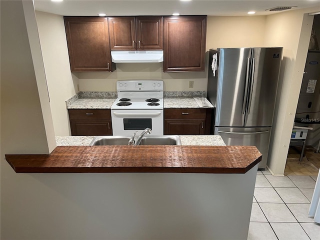 kitchen featuring under cabinet range hood, a sink, visible vents, electric stove, and freestanding refrigerator